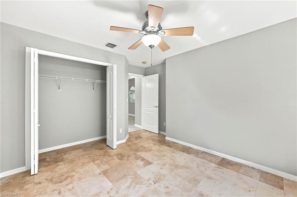 Spacious room featuring neutral tone walls, large format tile flooring, and a ceiling fan with integrated lighting