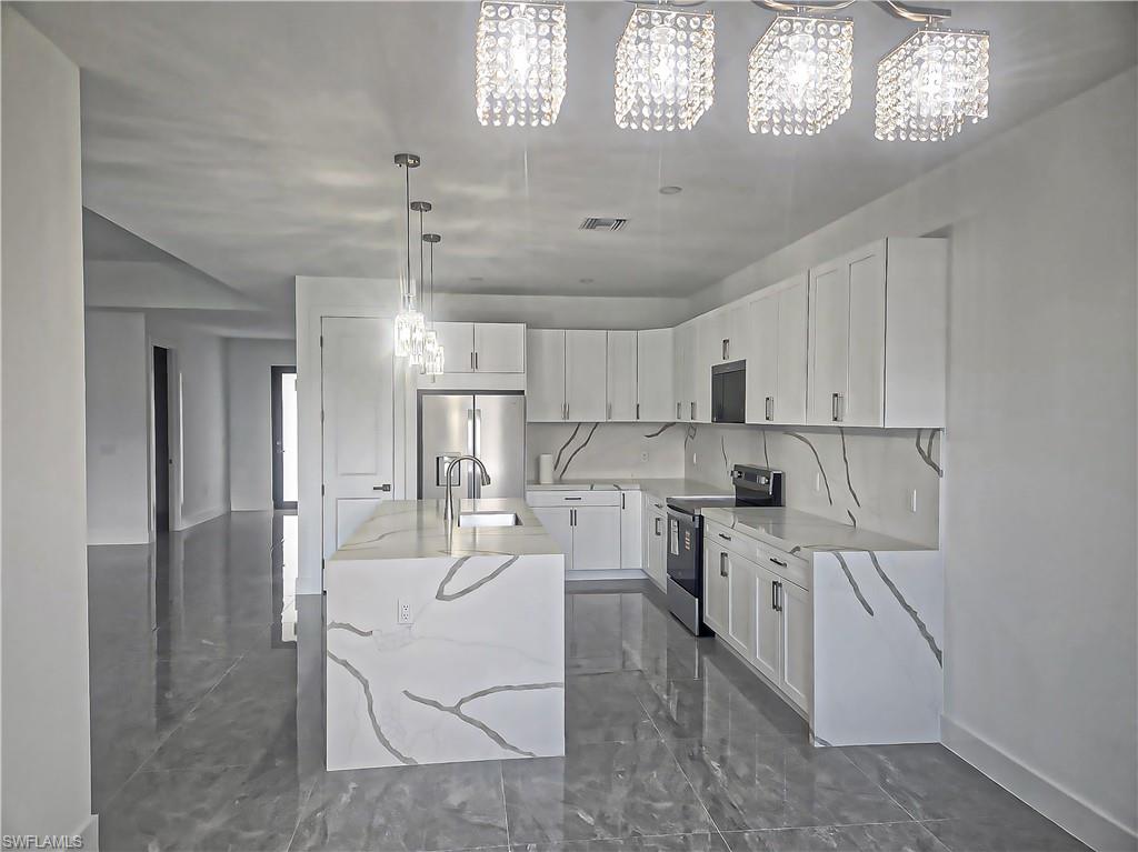 Modern kitchen featuring a waterfall island, integrated sink, and stainless steel appliances
