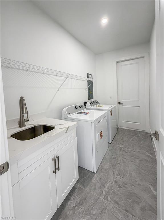 Laundry room featuring a utility sink with a brushed metal faucet, white cabinetry, and a stone-finish countertop