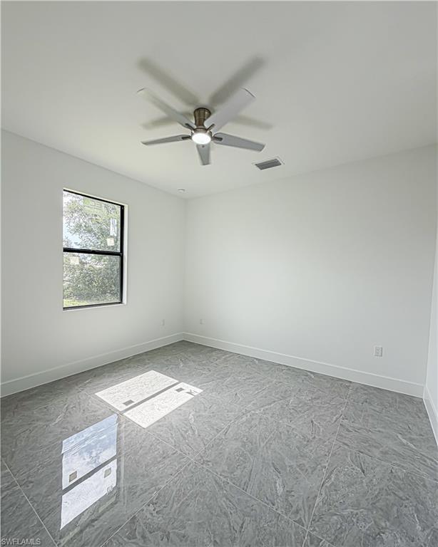 Bright room featuring polished gray tile flooring, a modern ceiling fan with integrated lighting, a recessed ceiling light, a single-pane window with black trim, and crisp white baseboards