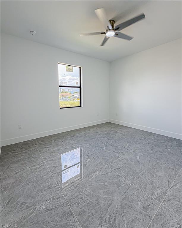 Spacious room featuring large format grey tile flooring, white baseboards, and a contemporary ceiling fan with integrated lighting