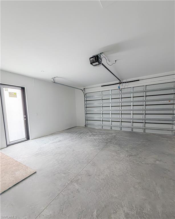 Spacious garage with a concrete floor, white painted walls, and an automatic garage door opener