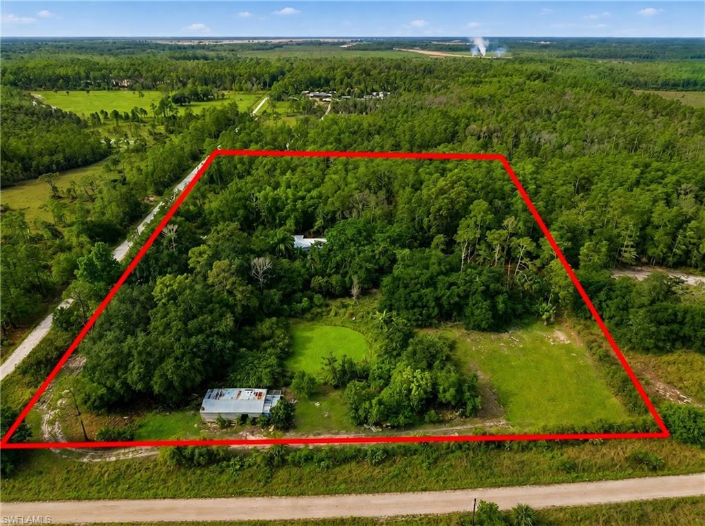 Expansive wooded lot featuring a designated building envelope, natural water feature, existing structures, and direct road access