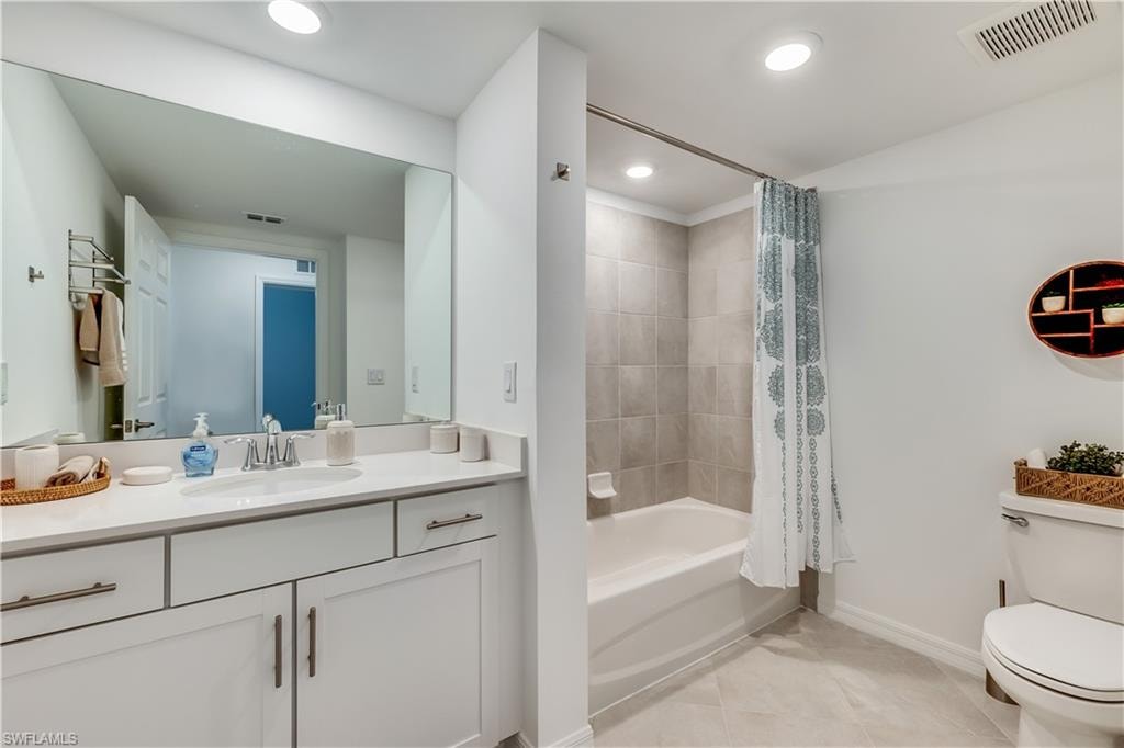 Full bathroom featuring tile floors, vanity, toilet, and shower / bath combo with shower curtain