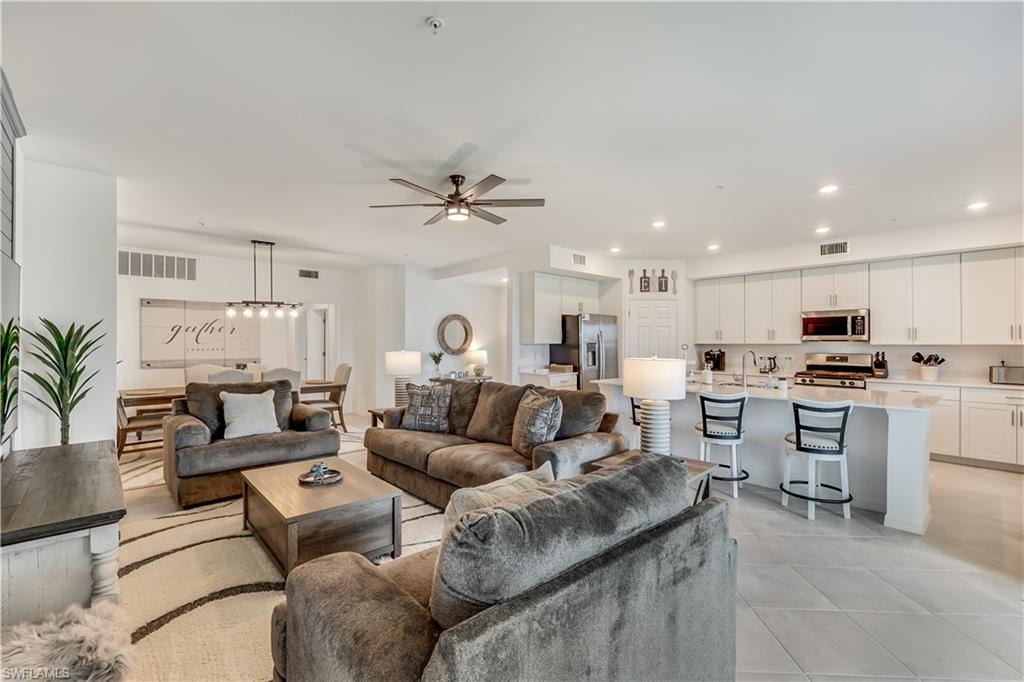 Living room with sink, light tile flooring, and ceiling fan