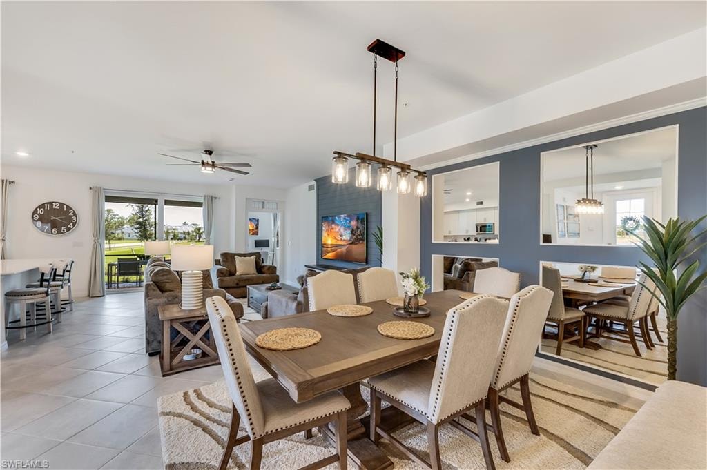 Tiled dining space featuring ceiling fan with notable chandelier and a wealth of natural light