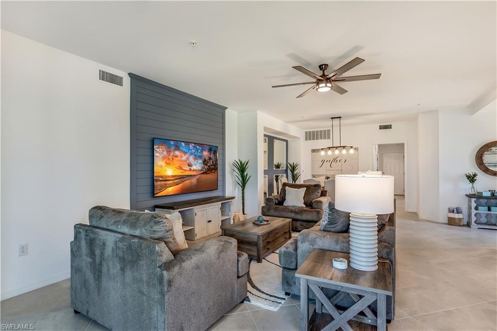 Living room featuring tile flooring and ceiling fan with notable chandelier