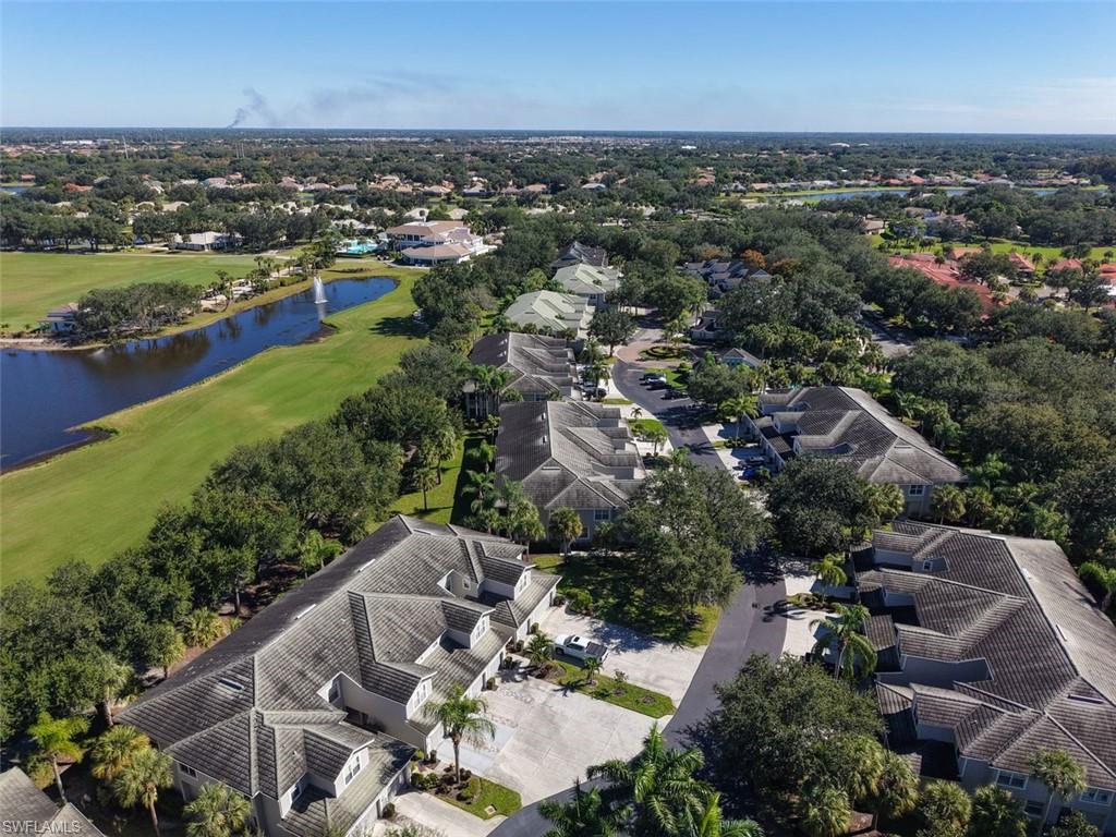 Aerial view of residential area featuring a golf course and a nearby body of water