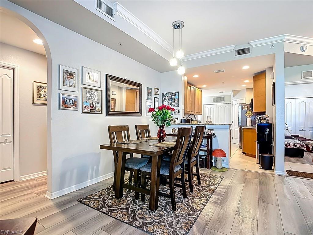 Dining space featuring arched walkways, light wood-style floors, recessed lighting, and crown molding
