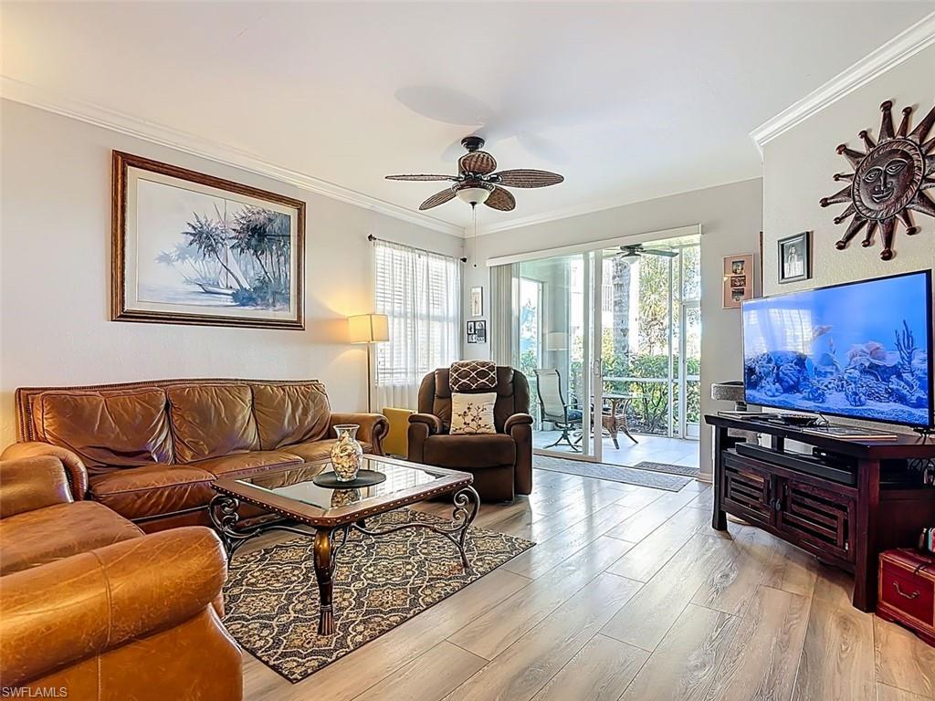 Living room with ornamental molding, light wood-style floors, and a ceiling fan