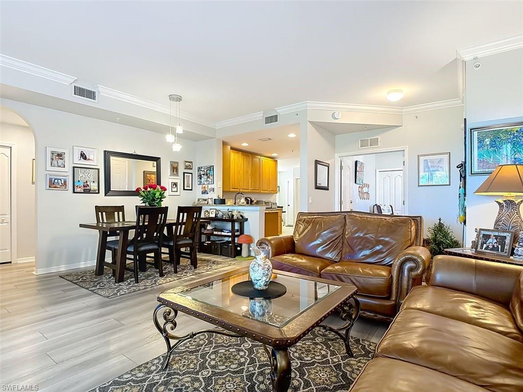 Living area featuring arched walkways, ornamental molding, and light wood-type flooring