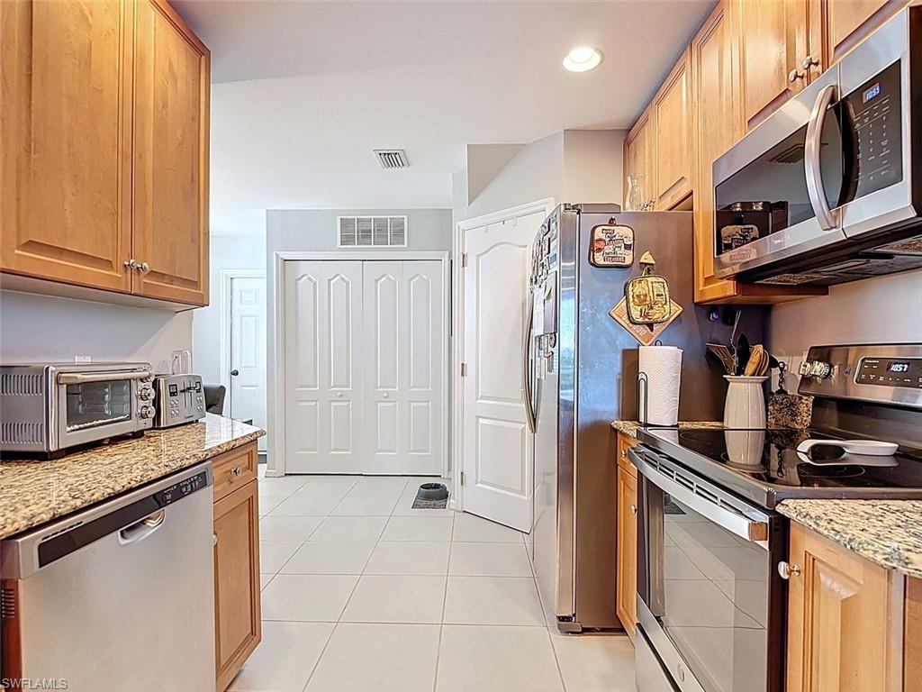 Kitchen featuring appliances with stainless steel finishes, light stone countertops, light tile patterned floors, and recessed lighting