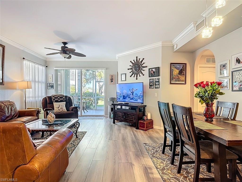 Living room featuring arched walkways, crown molding, wood finished floors, and ceiling fan