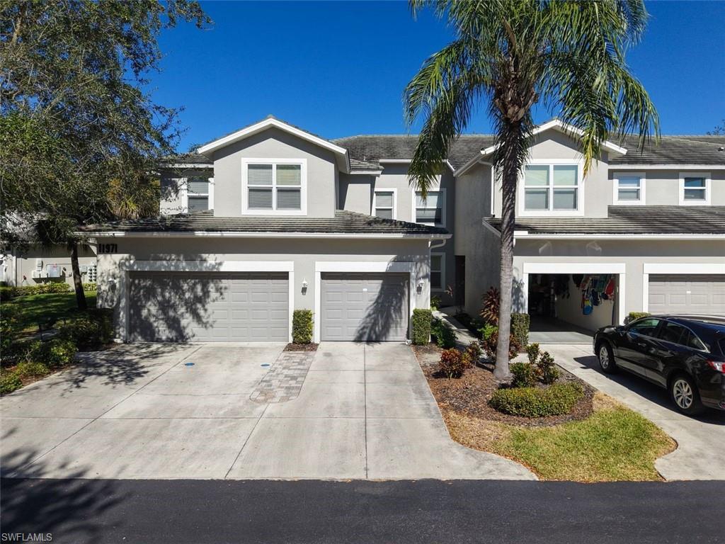Traditional home with stucco siding, concrete driveway, a tile roof, and a garage