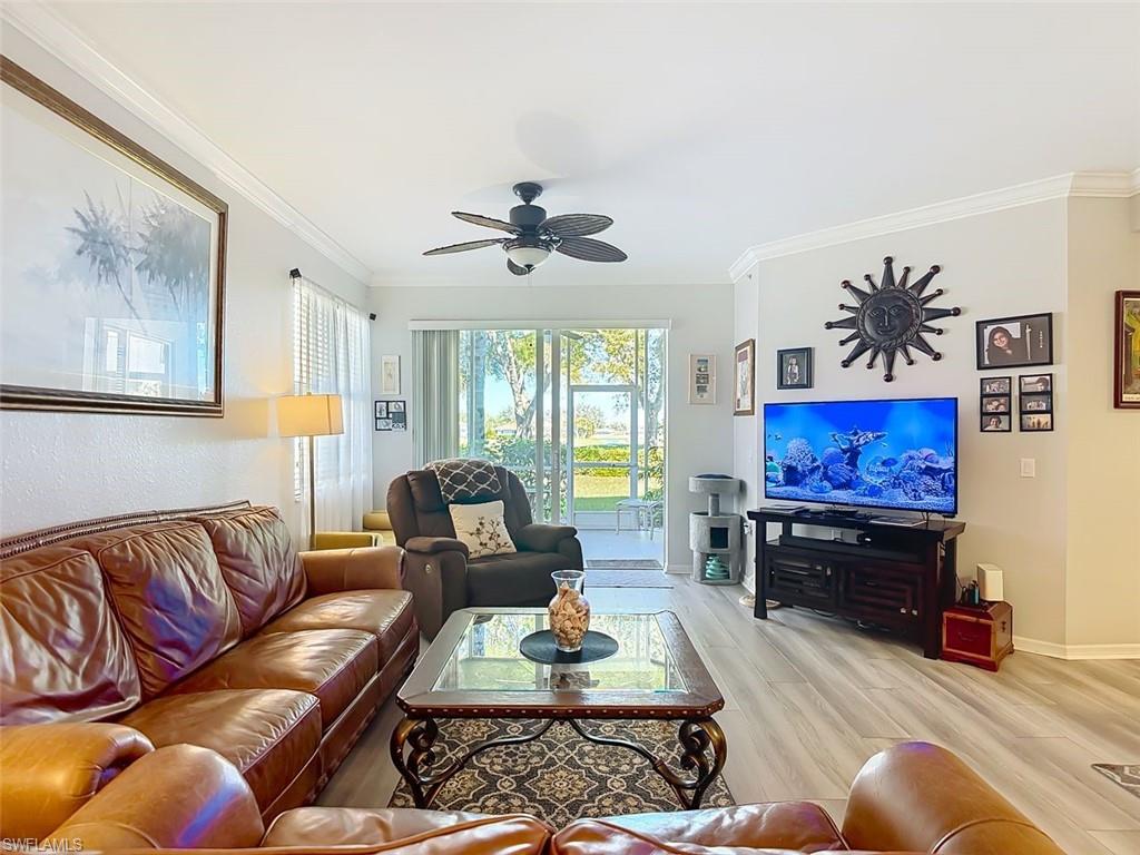 Living room with crown molding, wood finished floors, and a ceiling fan