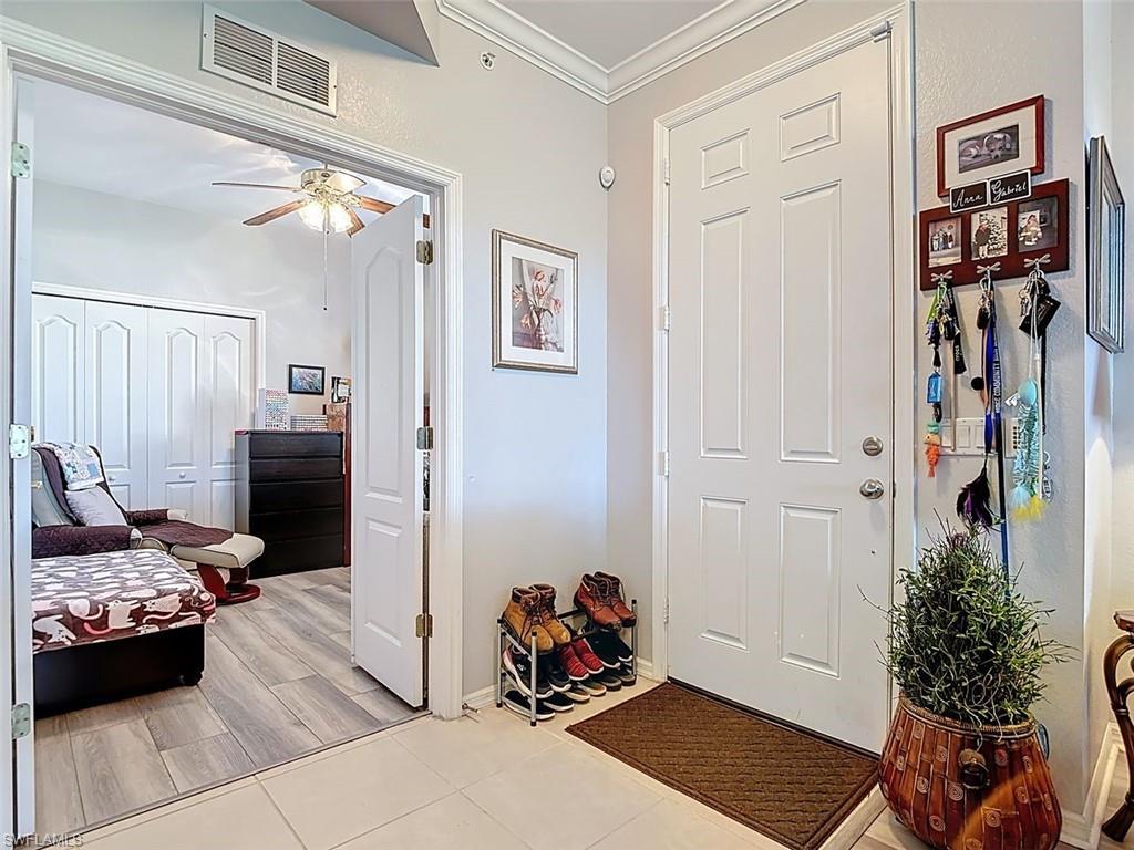 Entrance foyer with ornamental molding, ceiling fan, and wood finish floors