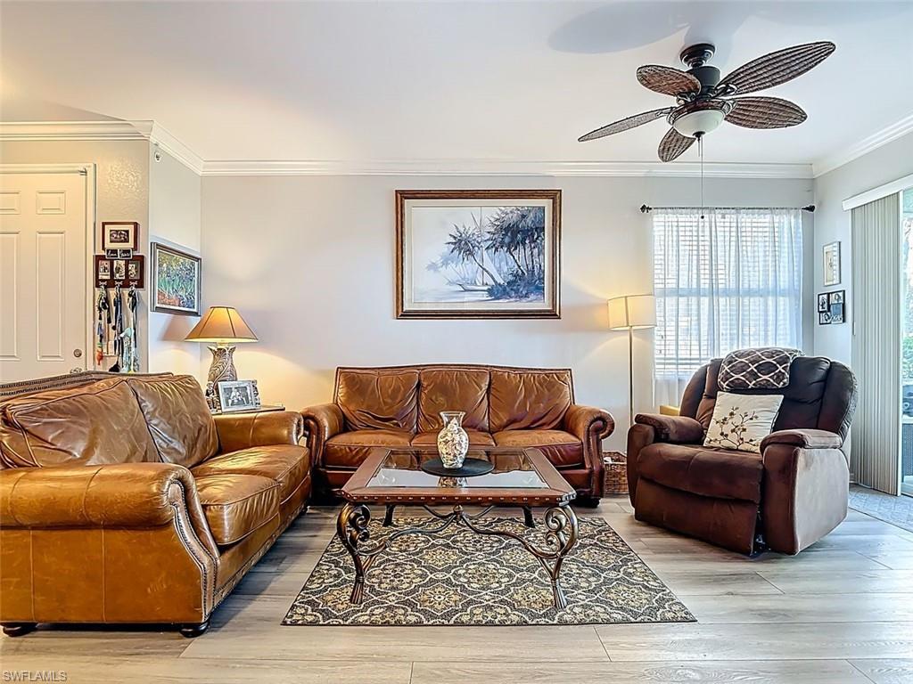 Living room with crown molding, wood finished floors, and ceiling fan