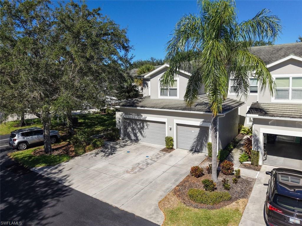 Traditional-style home with stucco siding, concrete driveway, an attached garage, and a tile roof