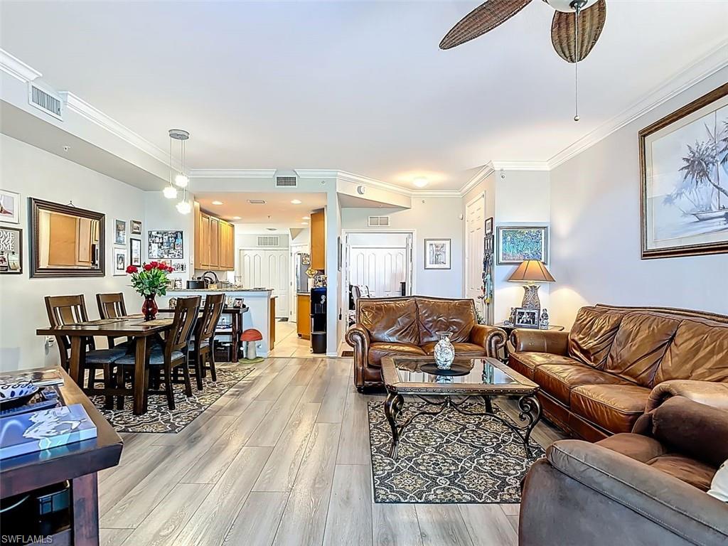 Living room featuring ornamental molding, light wood-type flooring, and a ceiling fan