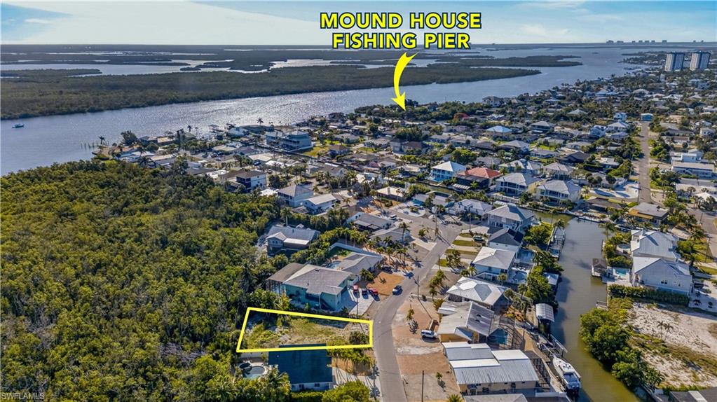 Cleared lot with surrounding residential properties, featuring paved road frontage - Virtually Edited Image