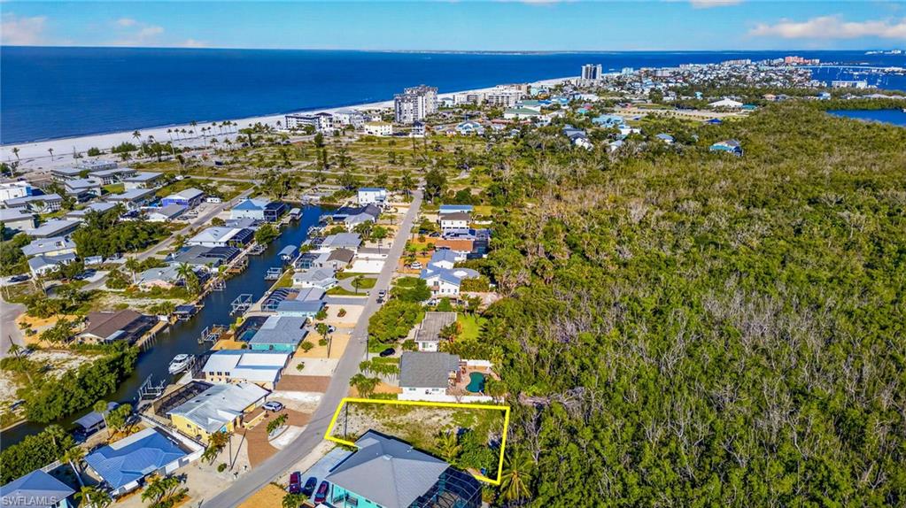 Cleared lot with direct road frontage, situated among residential properties and dense natural foliage - Virtually Edited Image