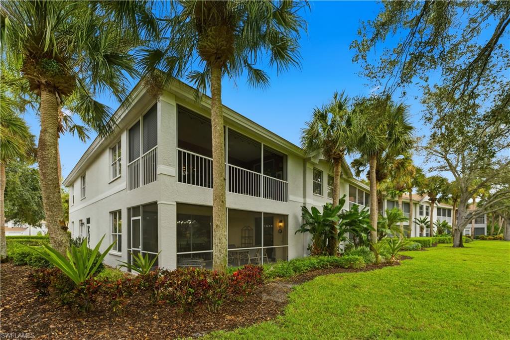 Back of property featuring a sunroom, stucco siding, a yard, and a balcony