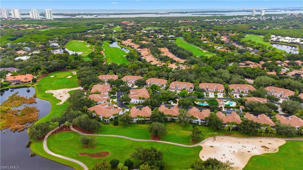 Aerial perspective of suburban area featuring a golf course and a nearby body of water
