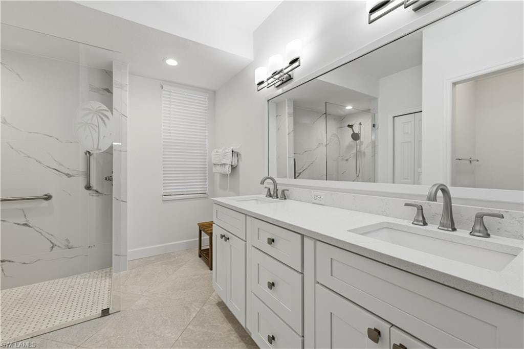 Full bath with double vanity, a marble finish shower, and recessed lighting