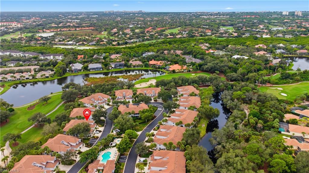 Aerial view of property and surrounding area featuring nearby suburban area, a large body of water, and a golf course