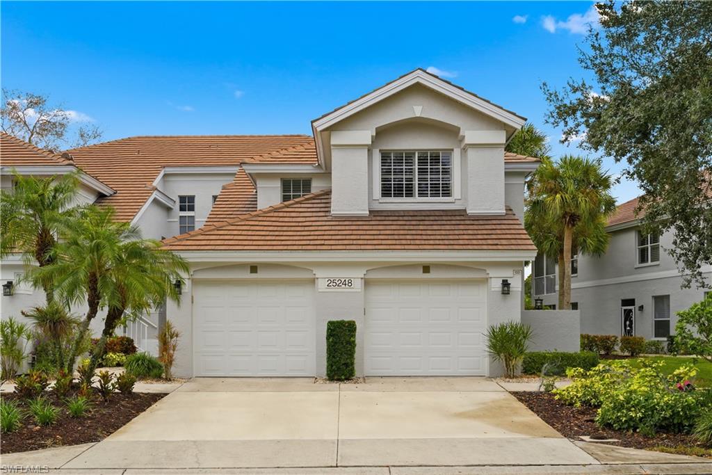 View of front of property with driveway, a garage, stucco siding, and a tiled roof