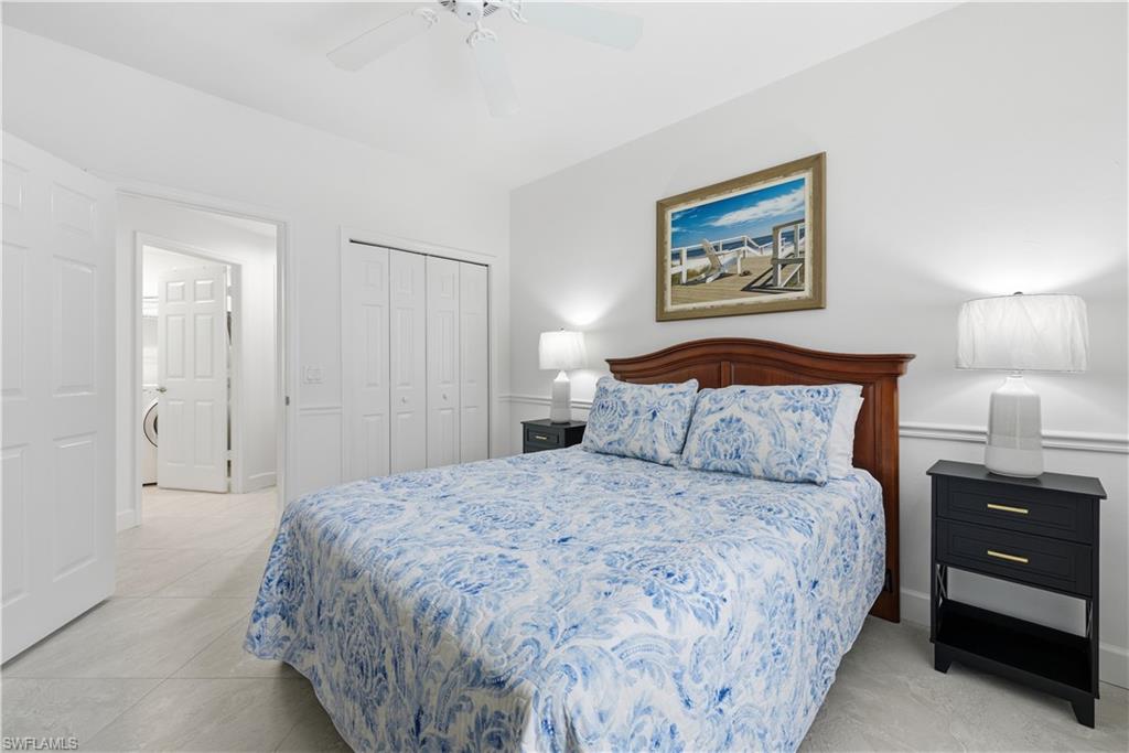 Bedroom with a closet, a ceiling fan, light tile patterned floors, and washer / dryer