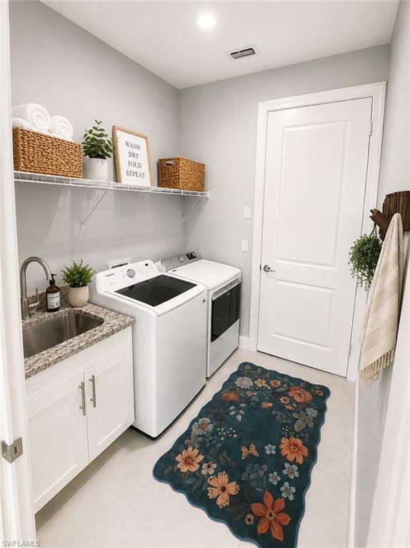 Dedicated utility space featuring a stainless steel sink, granite countertop, and white shaker-style cabinetry