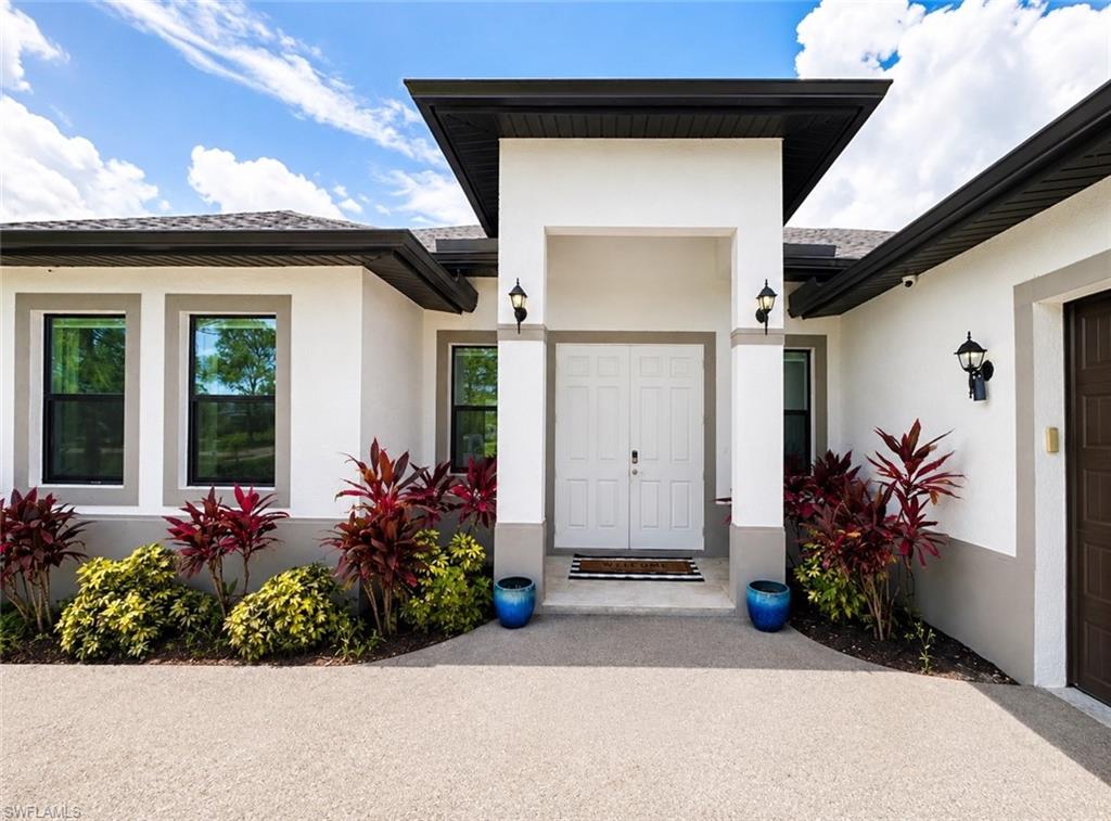 Contemporary exterior with a white stucco finish, dark gray trim, and a prominent double-door entry