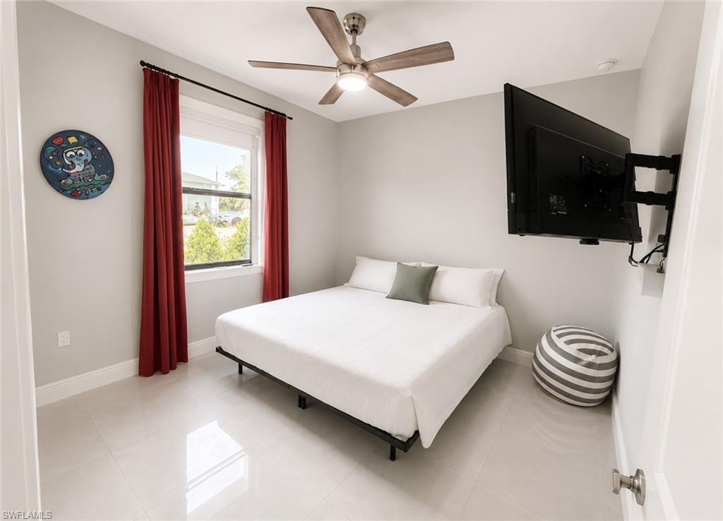 Second Bedroom Light-filled room featuring large format tile flooring, a window with exterior views, and a ceiling fan with integrated lighting