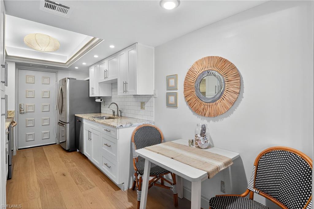 Eat in Kitchen featuring recessed lighting, white cabinets, light stone countertops, and decorative backsplash
