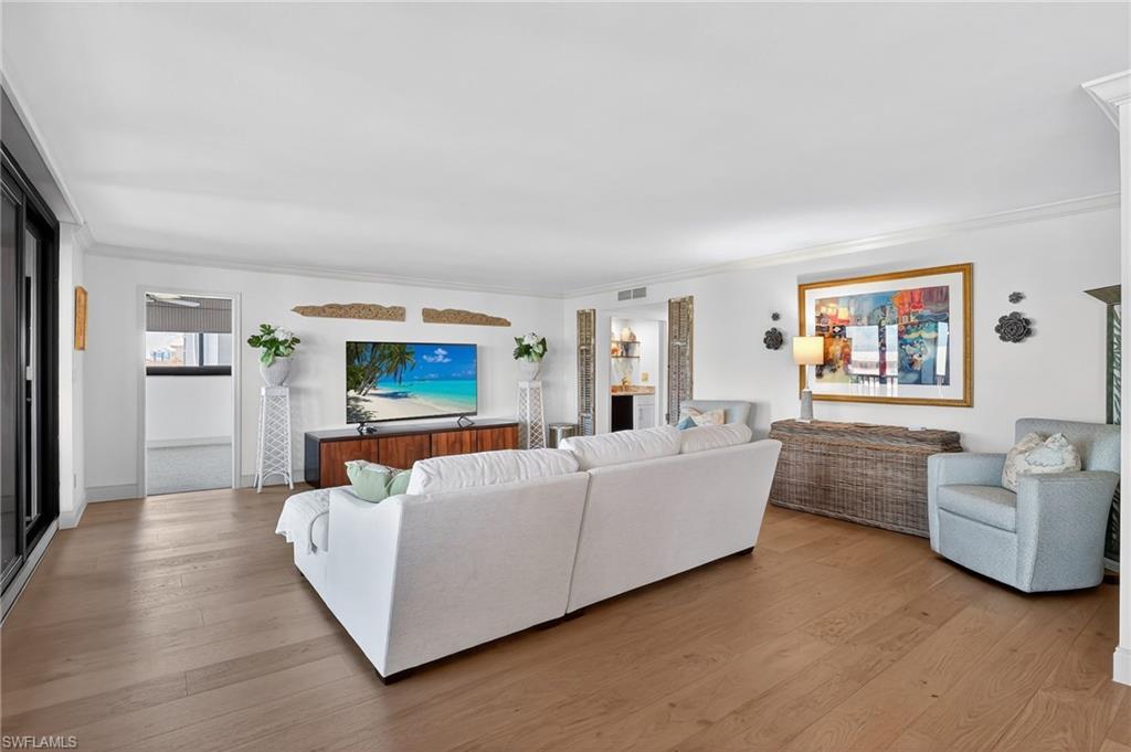 Great room with light wood finished floors and ornamental molding