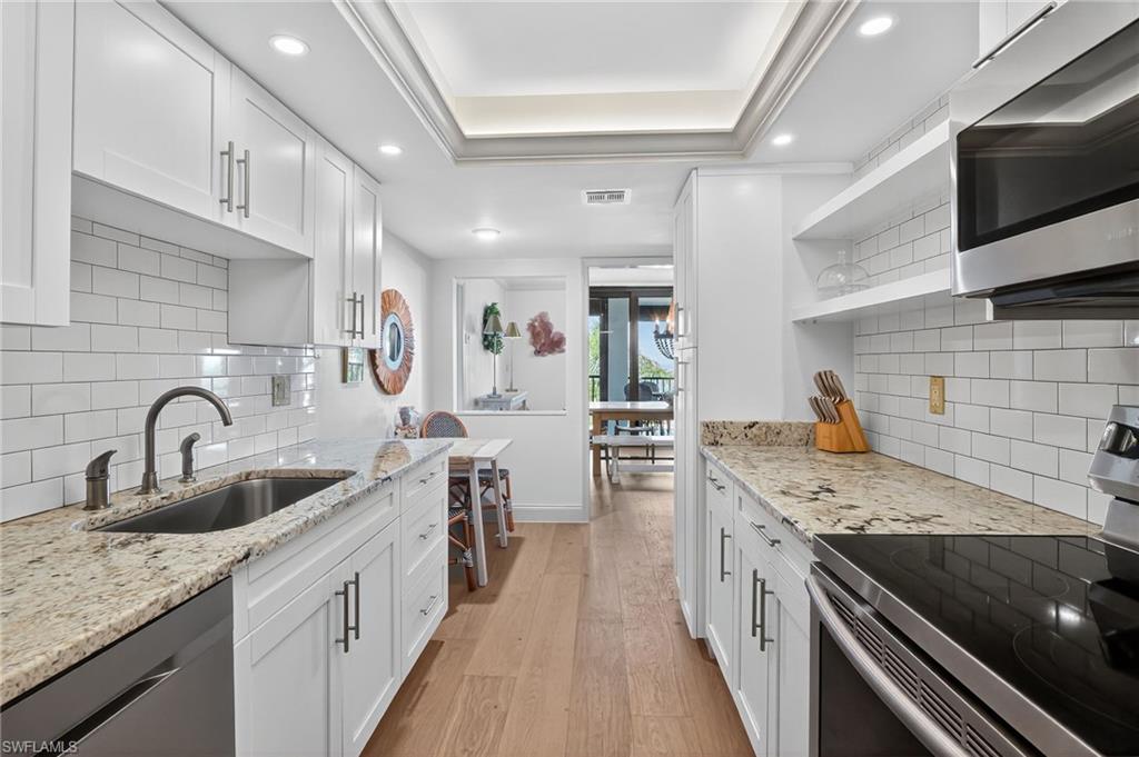 Kitchen featuring appliances with stainless steel finishes, open shelves, light wood finished floors, white cabinets, and recessed lighting
