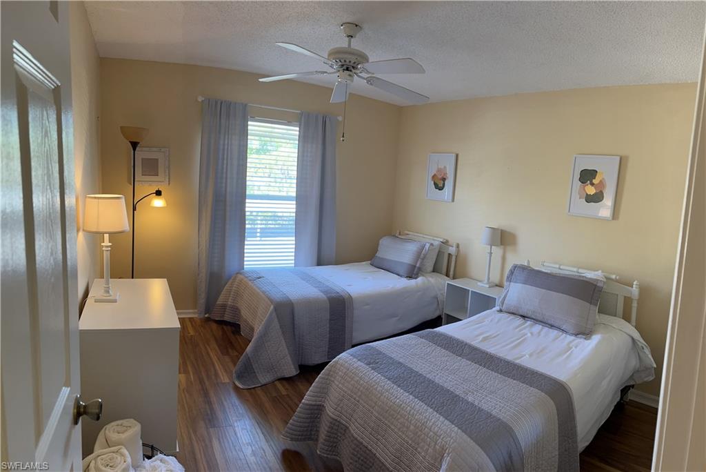 Interior room featuring wood-finish flooring, a window with horizontal blinds and light blue drapes, and a ceiling fan with integrated lighting