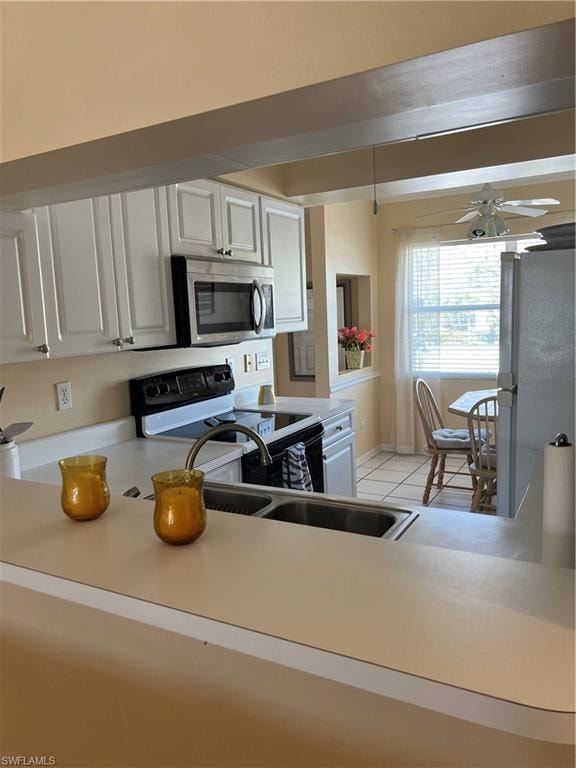 Kitchen featuring white paneled cabinetry, stainless steel microwave, black electric range, and a double-basin stainless steel sink with a high-arc faucet