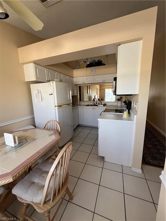 Kitchen featuring white cabinetry, light-toned countertops, and tile flooring