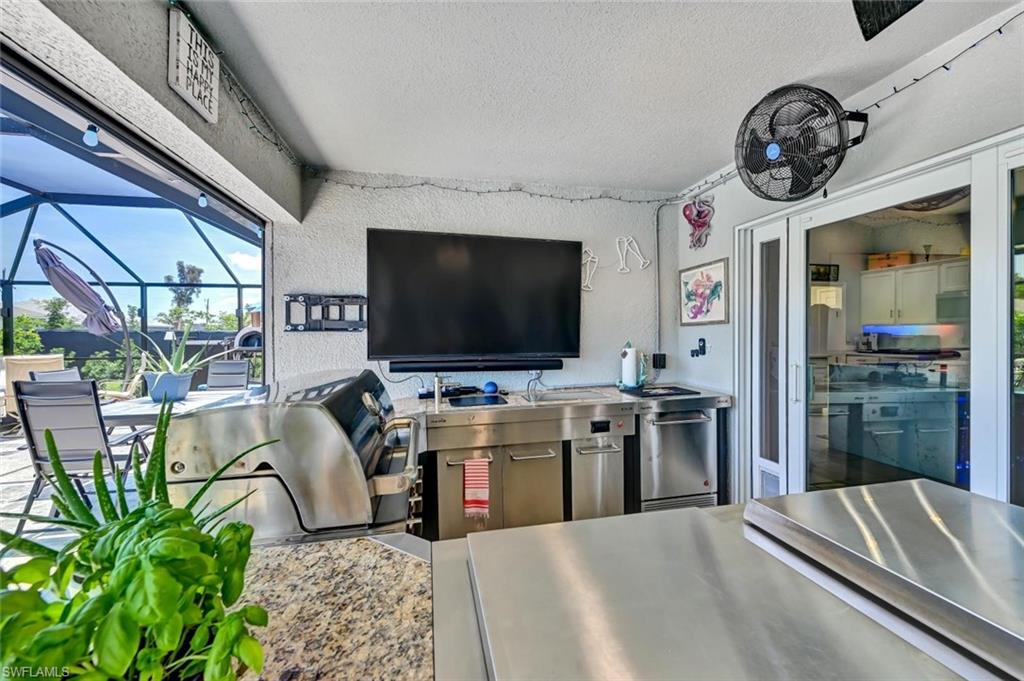 Outdoor kitchen featuring stainless steel cabinetry, integrated grill, and a built-in outdoor television