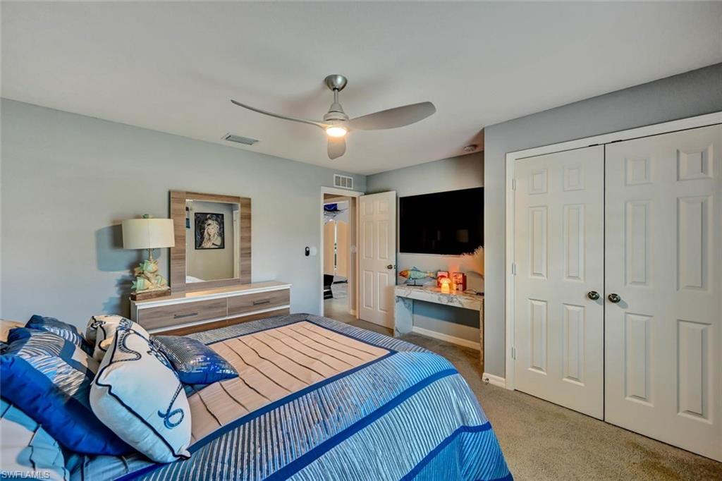 Bedroom featuring light gray walls, textured carpeting, a ceiling fan with integrated lighting, and white bi-fold closet doors