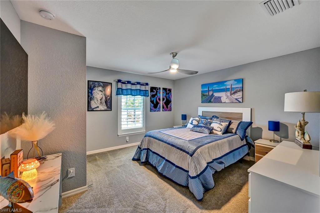 Carpeted room featuring a ceiling fan with integrated lighting, window with white plantation shutters, and light gray painted walls