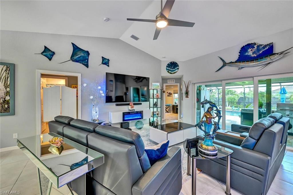 Spacious living area featuring vaulted ceilings, a ceiling fan, and tile flooring