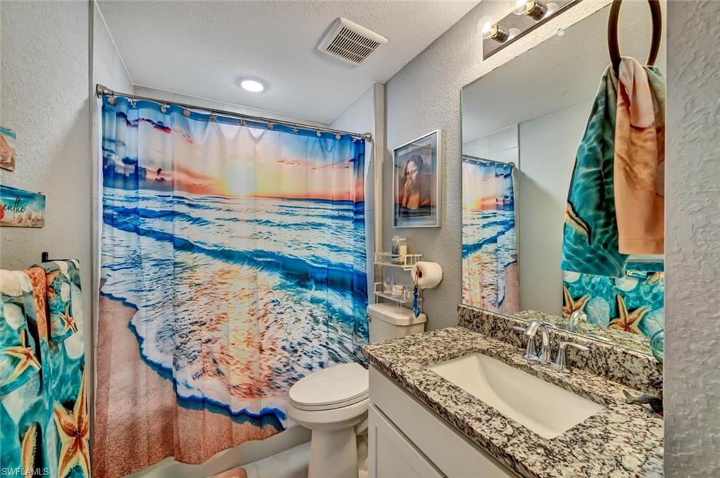 Bathroom featuring a granite-finish vanity countertop, integrated sink, and overhead lighting fixture