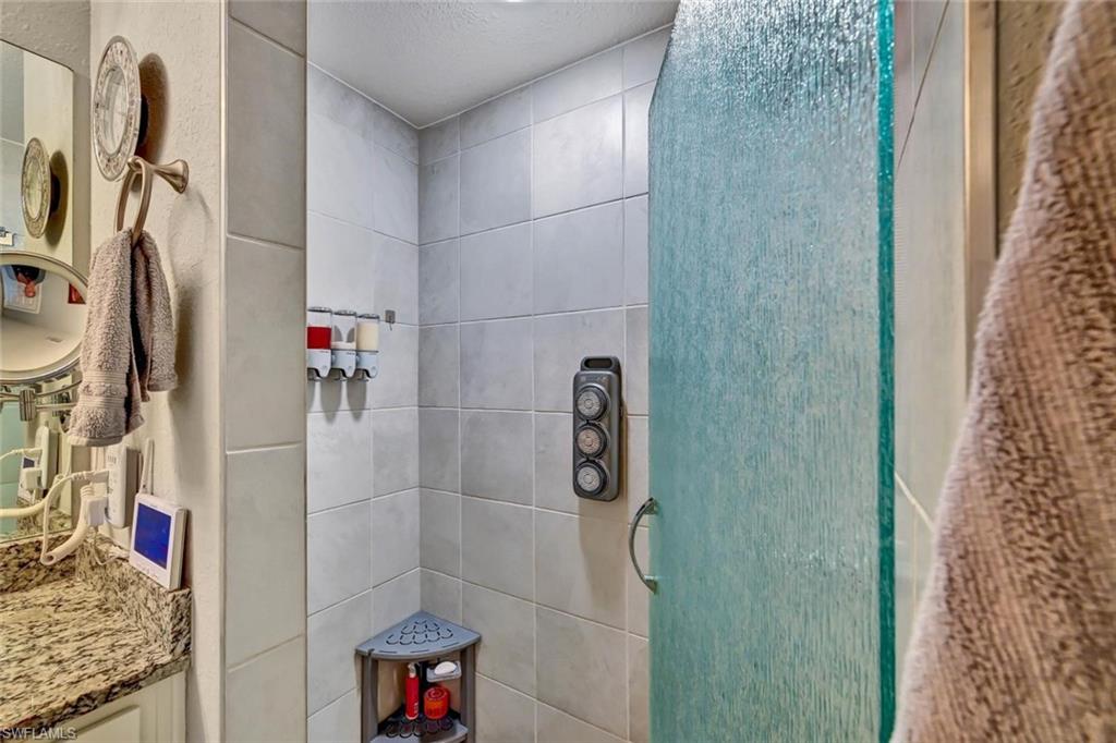 Shower enclosure featuring a frosted glass door, tiled walls, and a corner shelving unit