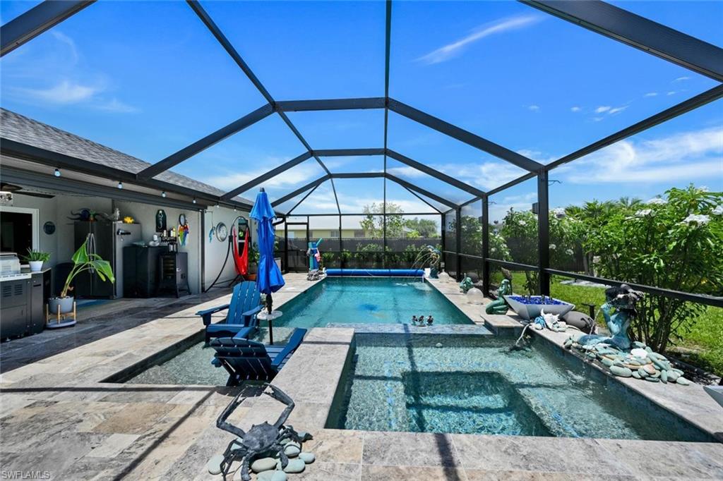 Screened outdoor living area featuring a swimming pool, integrated spa, and expansive patio