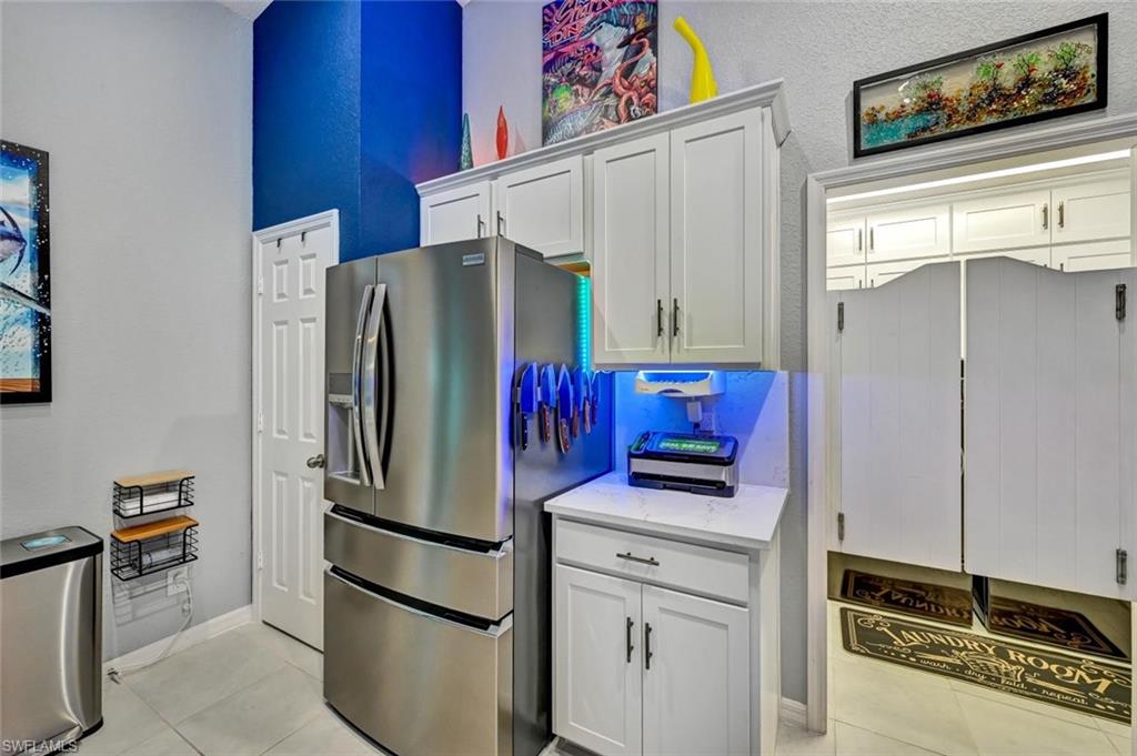 Functional utility area featuring white shaker cabinetry, an integrated countertop, and tile flooring