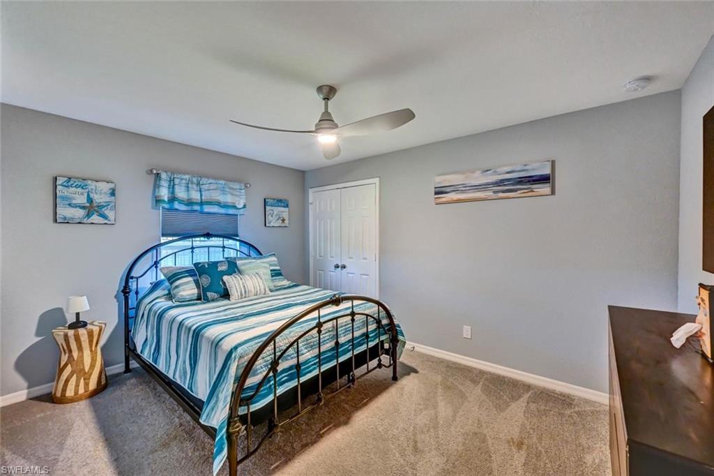 Bedroom featuring neutral-toned walls, textured carpeting, and a ceiling fan with integrated lighting