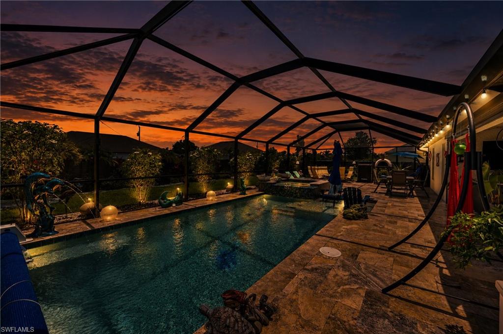 Screened pool enclosure featuring a rectangular swimming pool, integrated spa, and expansive paver patio